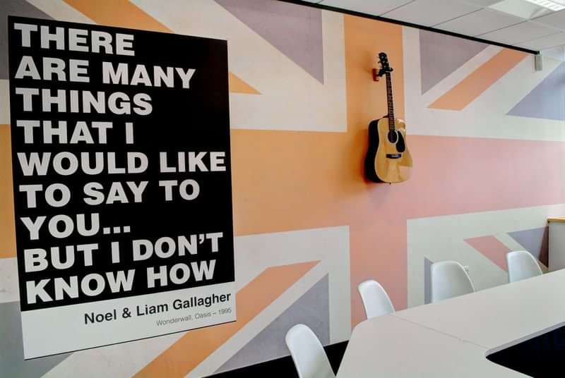 Language travel classroom with British decor and motivational music quote.
