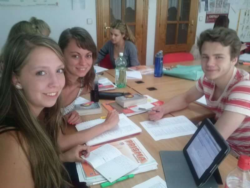 Students studying at an international language school, sharing materials, and interacting.