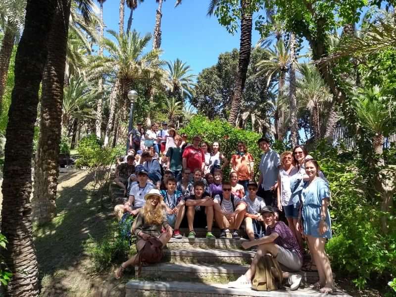 Een groep studenten op taalreis poseert buiten op een trap.