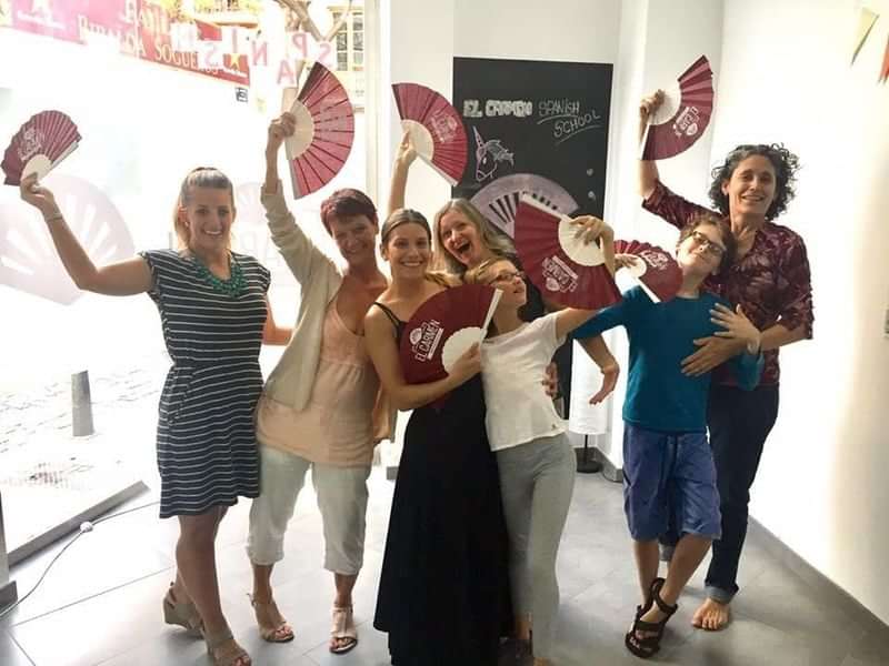 Group enjoying Spanish culture with traditional fans at a language school.