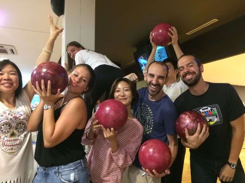 Groep internationale reizigers geniet van een bowlingavond tijdens taalreis.
