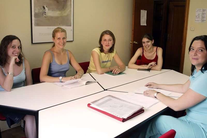A small group language class with instructor and students at a table.