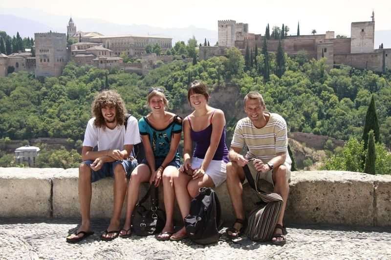 Group of young tourists with a castle background, enjoying their travel experience.