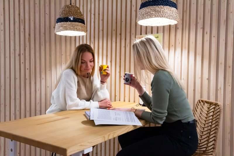 Two people discussing language travel materials over coffee in cozy setting.