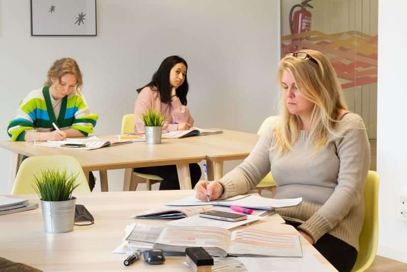 Students studying in a language course classroom, taking notes and reading.