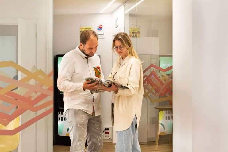 Two people studying a brochure near language travel office decor.