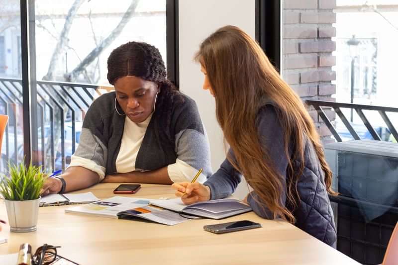 Two women studying language materials together at a table.