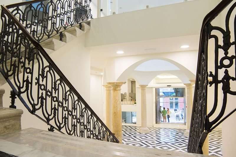 Elegant lobby with staircase, a potential language school entrance in historic building.