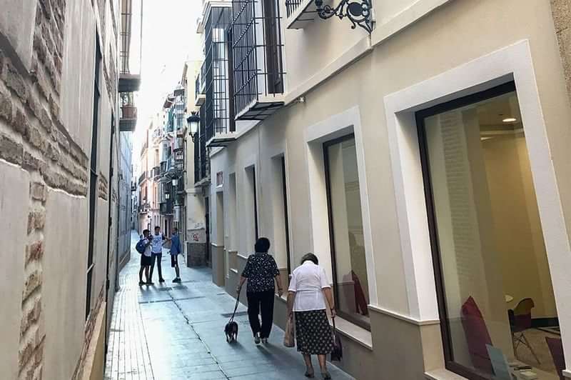 People walking down a narrow street, likely tourists exploring a city.