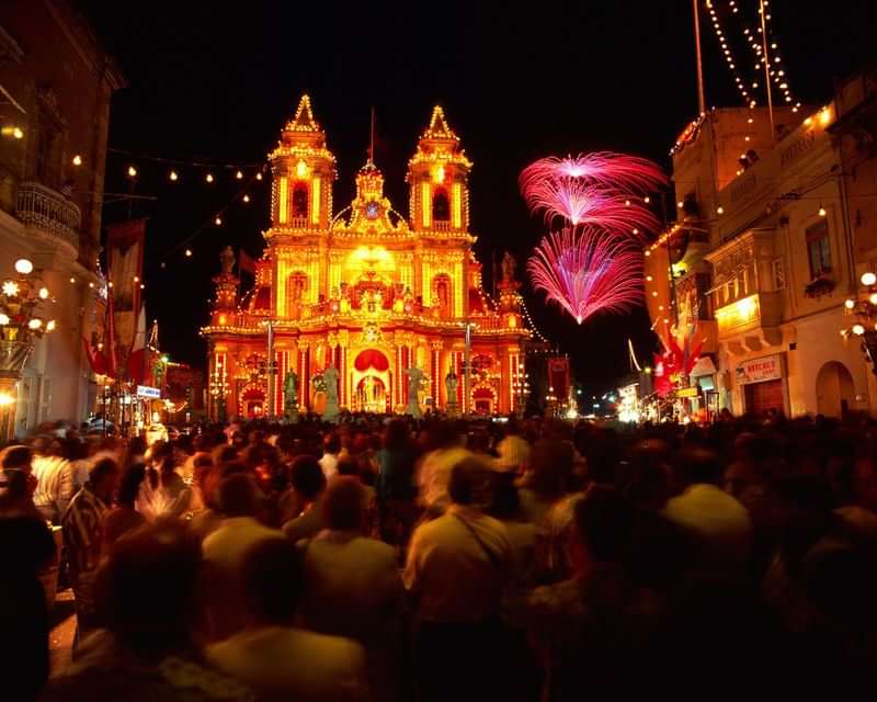 Festive celebration in a lively city with illuminated buildings and fireworks.