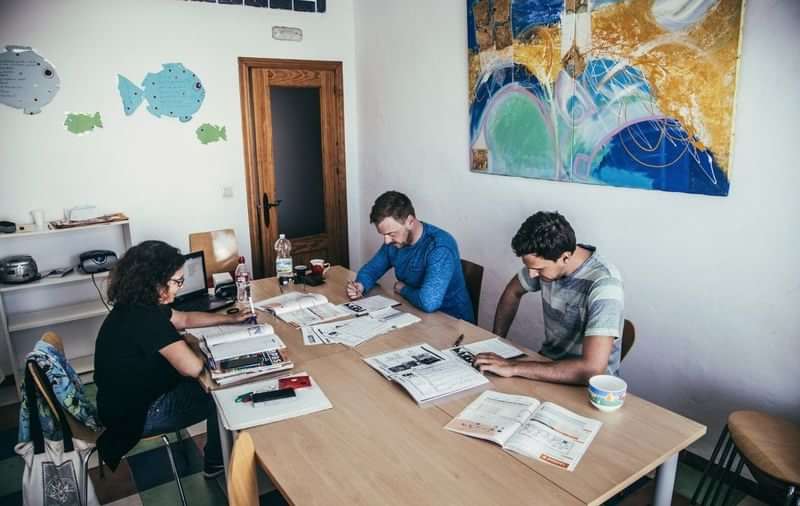 Three people studying at a table with language materials.