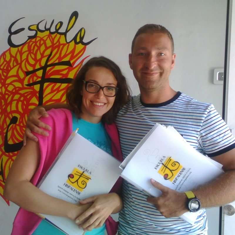 Students at a Spanish language school holding study materials, smiling.