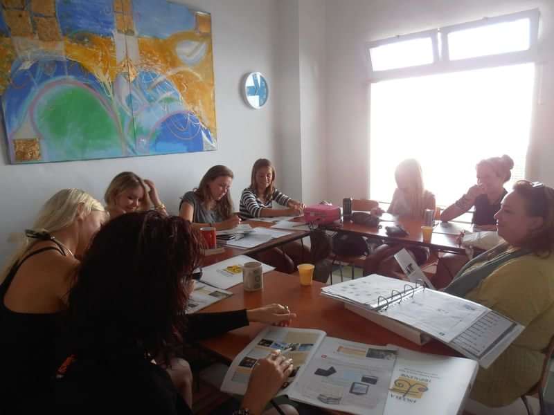 Group learning a language in a bright, comfortable classroom setting.