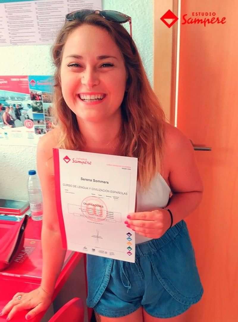Woman proudly displays language course completion certificate.