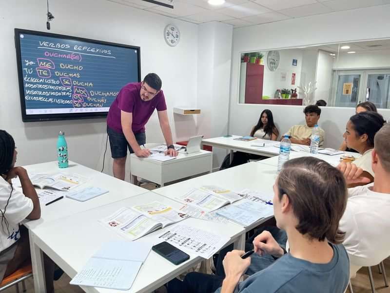 Classroom with students learning verbs, likely in a language immersion program.