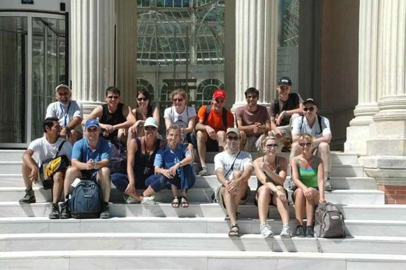 Groep jonge mensen zittend op trappen, mogelijk deelnemers aan taalcursus reis.