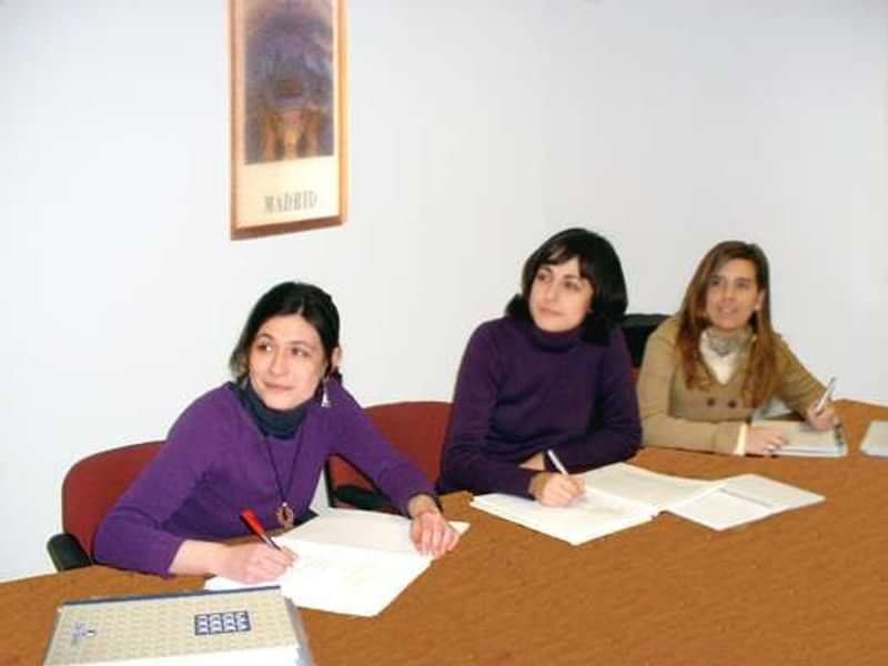 Three women in a classroom learning and writing notes.