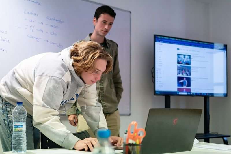 Studenten werken samen, laptop en scherm voor taalstudie of onderzoek.