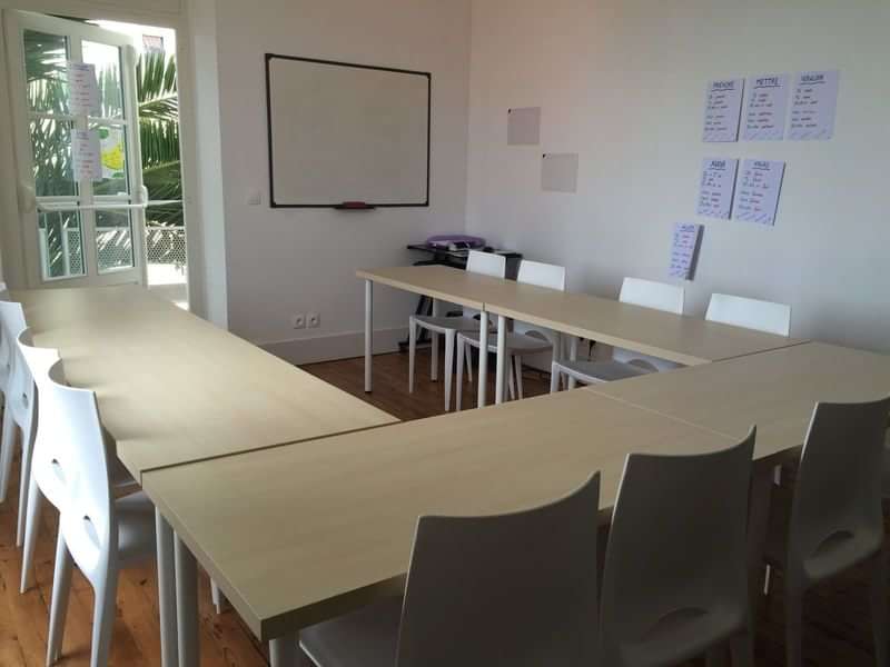 Classroom setup for language learning with whiteboards and tables.