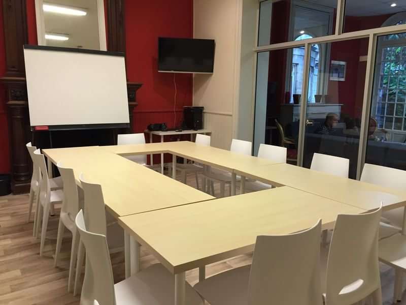 Language travel classroom setup with tables, chairs, whiteboard, and projector screen.