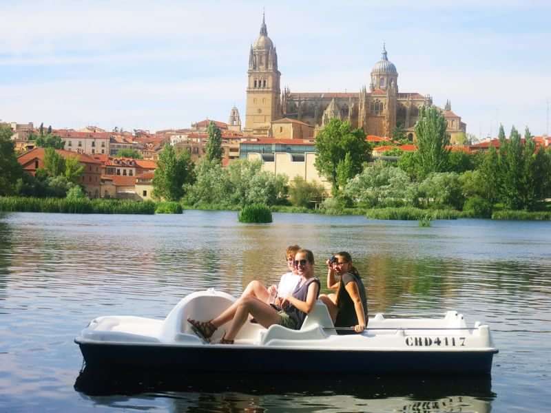 Two people in paddle boat, historic building in the background.