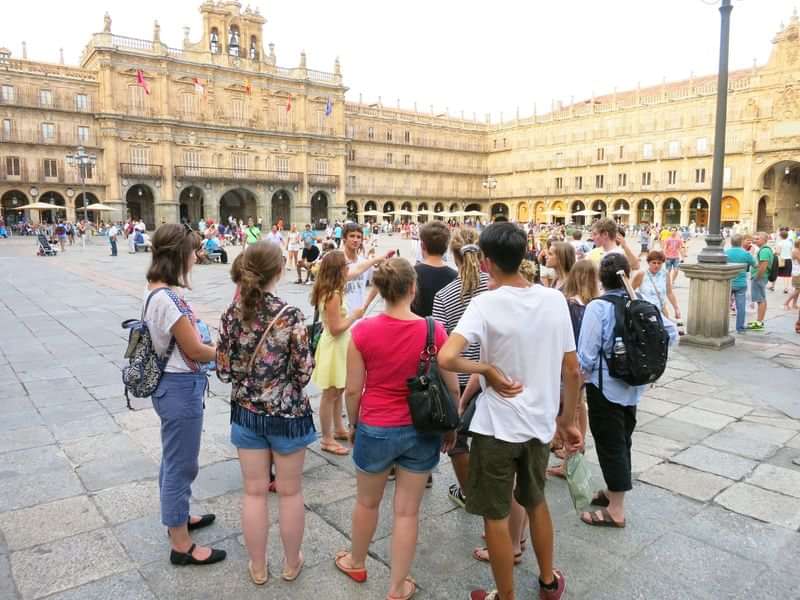 A tour group of language learners exploring a historic city plaza.