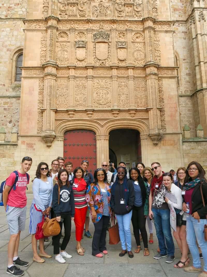 Group of travelers posing in front of an ornate historical building.