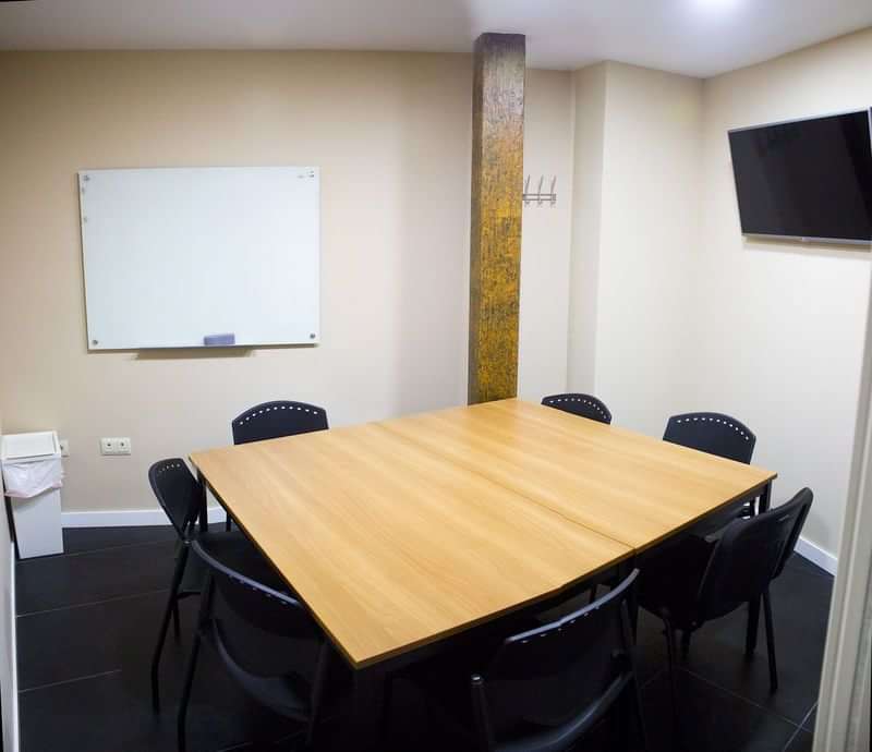 Small classroom for language learning equipped with whiteboard and table.