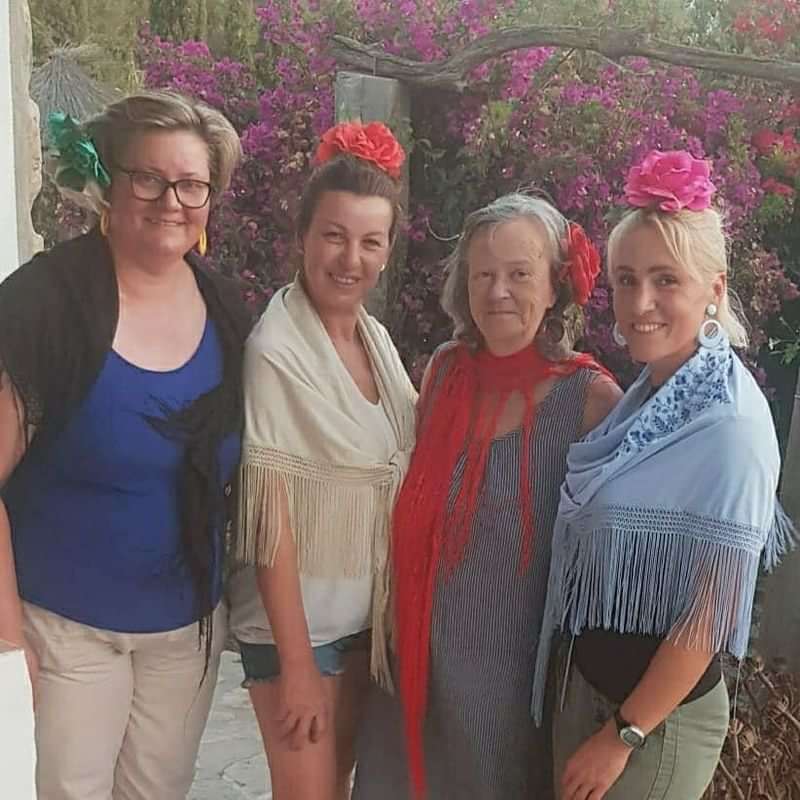 Women dressed in traditional Spanish attire with floral decorations.