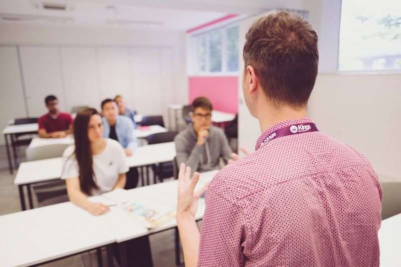 A teacher instructing a group of international students in a classroom.