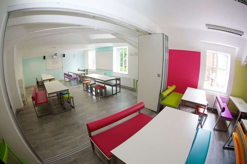 Bright classroom for language learning with colorful seating and whiteboard.