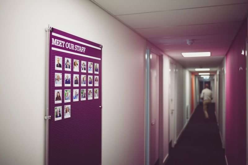 Hallway with staff board featuring photos, likely in a language school.