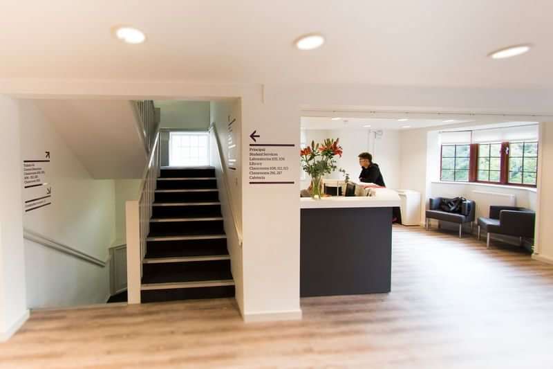 Language school reception area with staircase and informational signs.