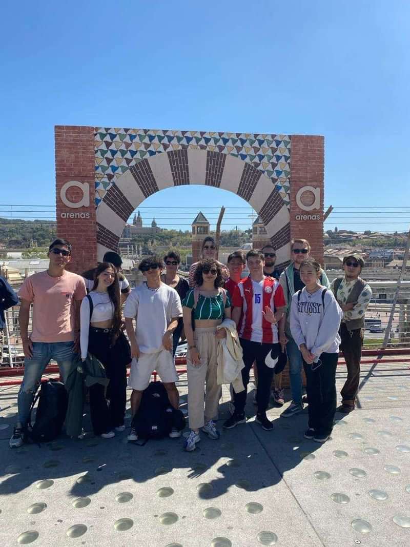 A group of students standing under a Spanish landmark arch.