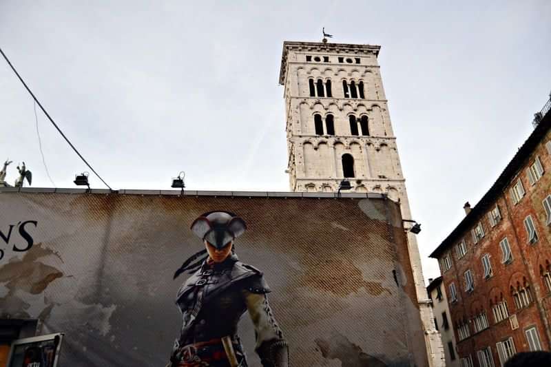 Medieval tower in European city with mural art on building wall.