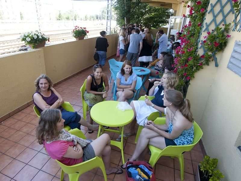 Groep studenten ontspannen, leren en sociaal bezig in een buitenruimte.