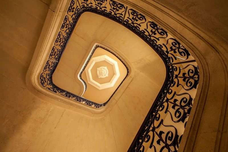 Ornate spiral staircase, possibly in historic hotel or cultural language institute.