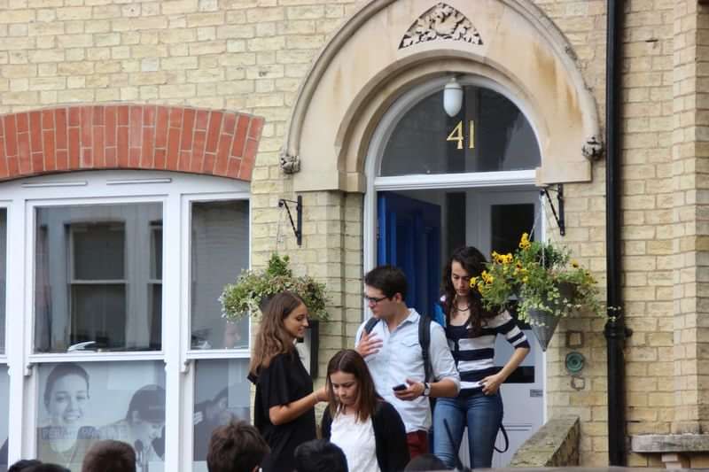 Students conversing outside a building, potentially discussing language travel plans.