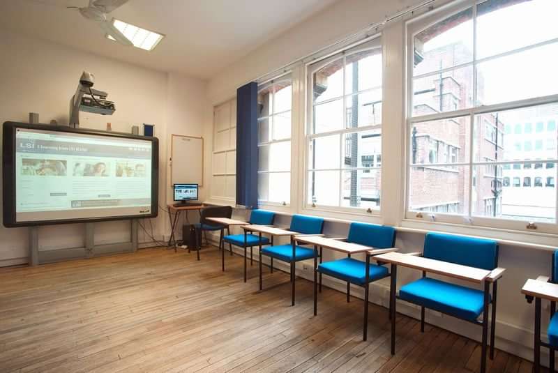A bright language classroom with desks, chairs, and an interactive whiteboard.