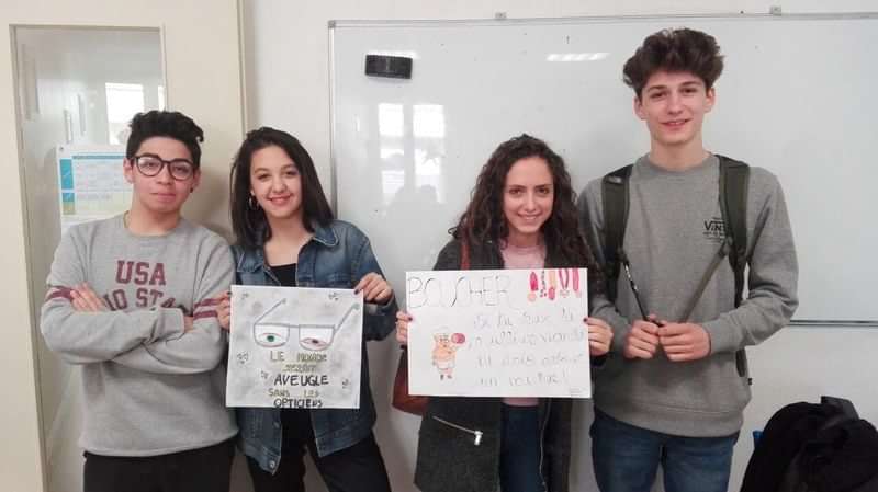 Students holding posters, possibly for a language exchange program or travel project.