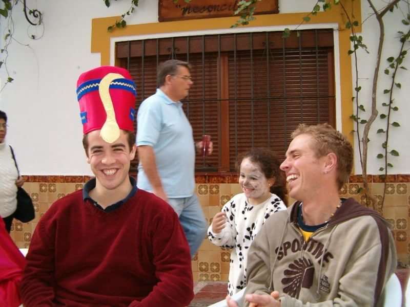 Twee lachende vrienden, kleurrijke hoed, straatfeest in een Nederlands sprekend land.