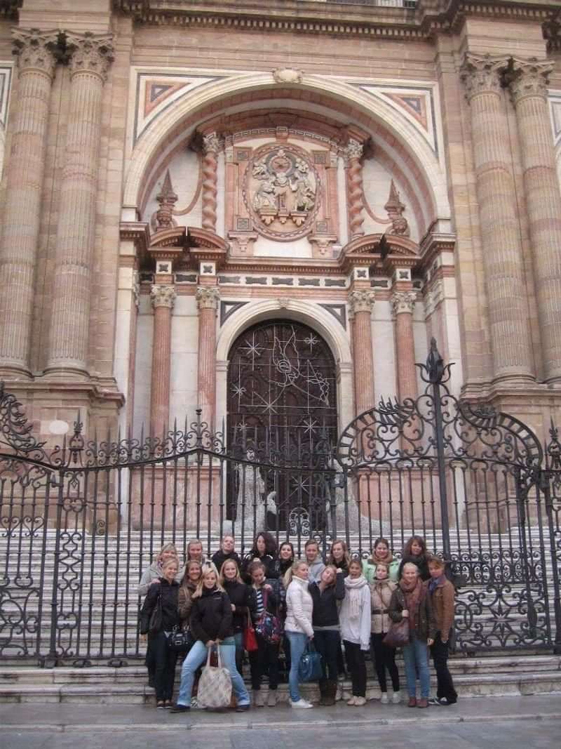 Groep toeristen poseert voor een historische kathedraal tijdens taalreis.