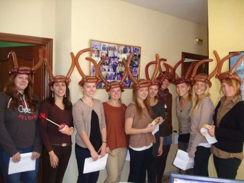 Studenten in een taalschool vieren feest met ballonhoeden.