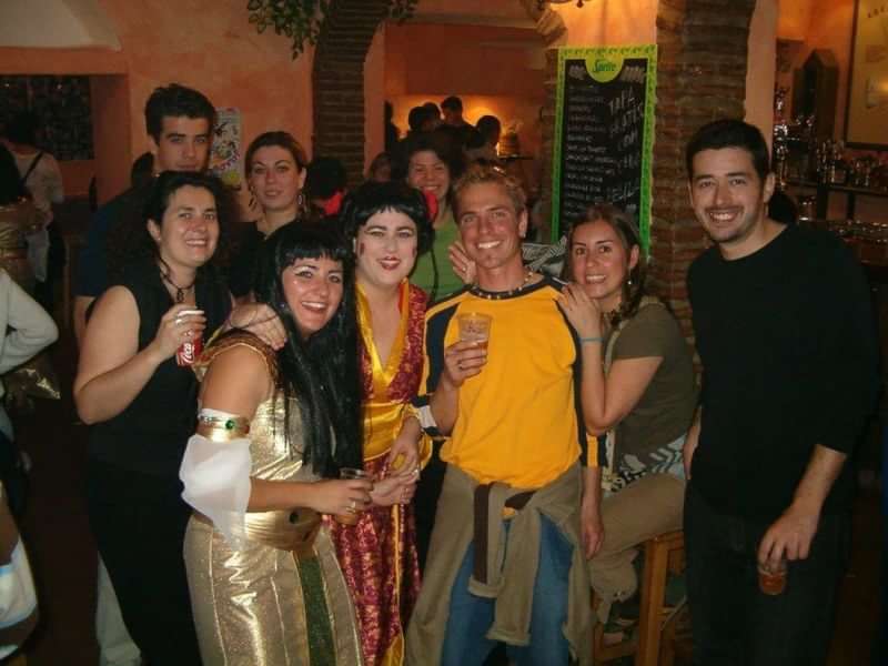 Group enjoying themed party, blending cultures, costumes, bar setting, language practice.