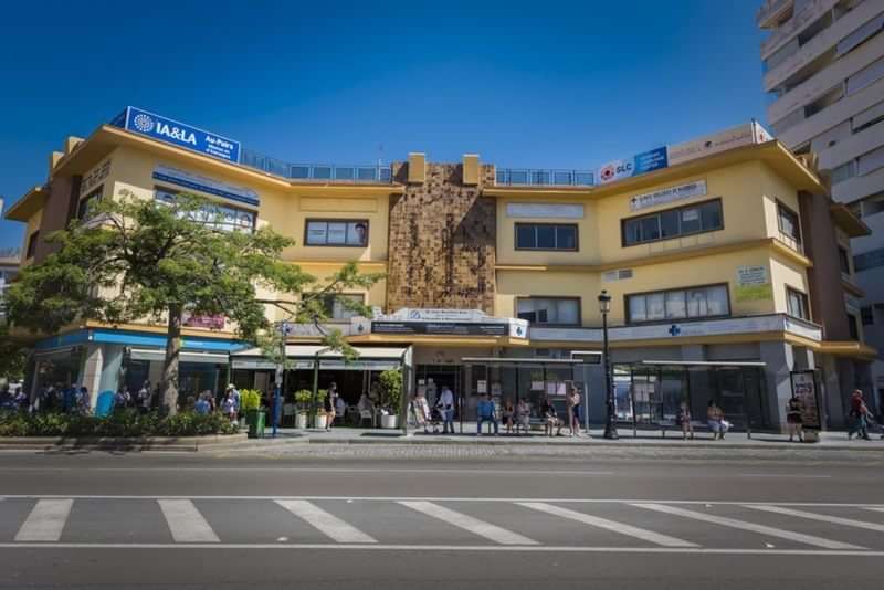 Language school building, people outside, sunny day, modern architecture, commercial area.