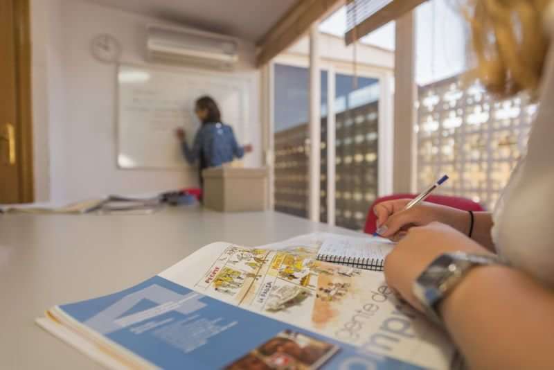 Taalstudenten in een leslokaal, docent schrijft op het bord.