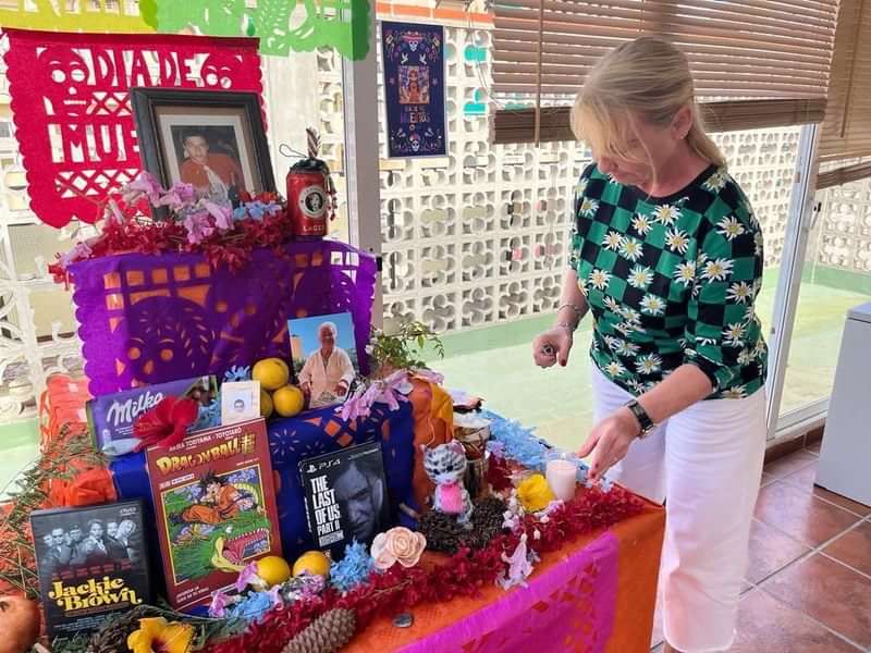 Día de Muertos altaar, vrouw plaatst kaars, Mexico cultureel erfgoed.