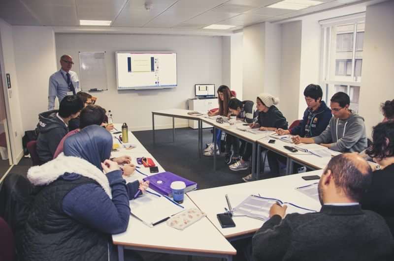 Language class with diverse students learning, practicing travel-related communication.