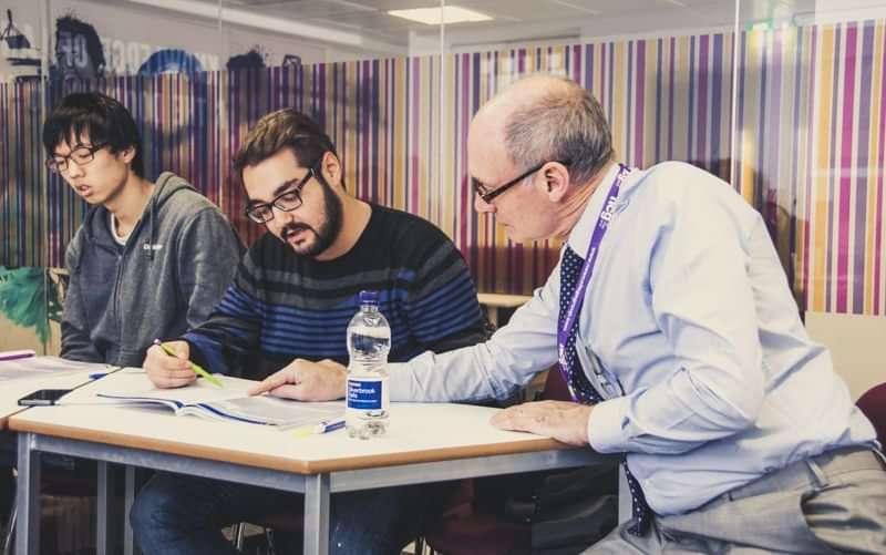 Students learning a language with an instructor in a classroom.