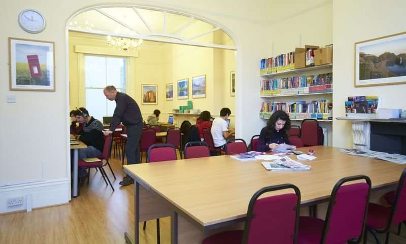 Students studying in a language school's library with educational resources.